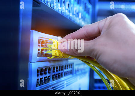 hand of administrator holding network cables connected to servers Stock Photo