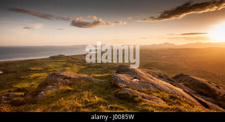 Sunset over Criccieth Bay and the Lleyn Peninsula as seen from the summit of Moel-y-Gest mountain near Porthmadog in Snowdonia, North Wales. Stock Photo