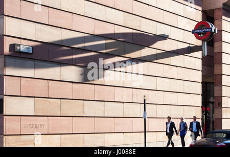 London, England, UK - July 3, 2009: Three pedestrians walk beneath a large London Underground roundel sign which casts a long shadow on the Number 1 P Stock Photo
