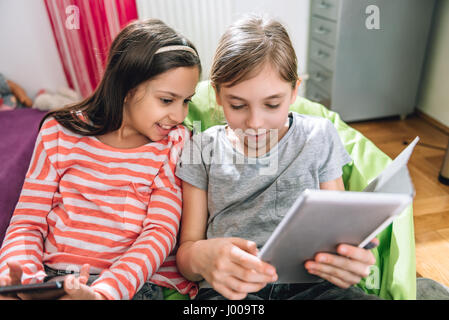 Two girls sitting in the kids room and using digital tablet Stock Photo