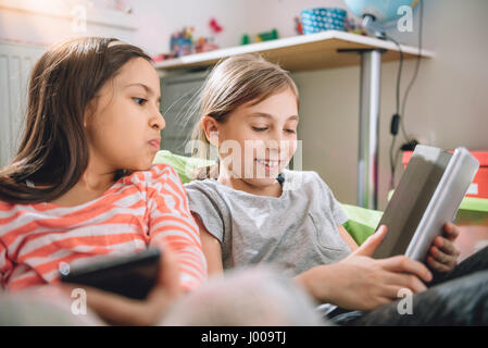 Two girls sitting in the kids room and using digital tablet Stock Photo