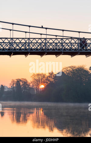 Chester, Cheshire, UK 8th April 2017 UK Weather, A cold start to the day but with temperatures warming up quickly on what could be the hottest day of the year so far for parts of the UK. Sunrise over a misty River Dee in the Roman City of Chester, Cheshire as pedestrians walk over the suspension bridge early morning © DGDImages/Alamy Live News Stock Photo