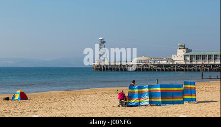 Bournemouth, Dorset, UK. 8th Apr, 2017. UK weather: lovely warm sunny day as visitors head to the seaside to make the most of the sunshine at Bournemouth beaches. Visitors with windbreaks - Bournemouth pier in the distance. Credit: Carolyn Jenkins/Alamy Live News Stock Photo