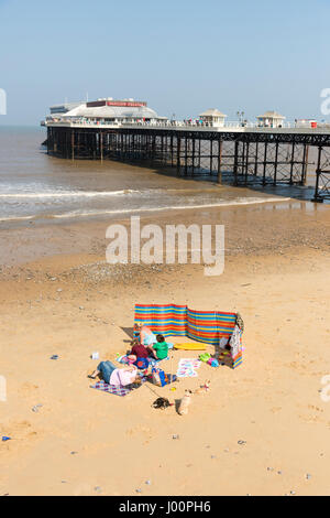 Cromer Norfolk UK 8th April 2017.  People sit on the beach by the famous pier and enjoy the glorious sunshine in warm spring weather. Temperatures rose to 19 degrees centigrade but there was a chilly wind. The fine weather is forecast to continue over the weekend. Credit Julian Eales/Alamy Live News Stock Photo