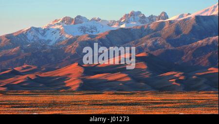 A vivid sunset over the Sangre de Cristo mountains at the Great Sand Dunes National Park and Preserve April 7, 2017 near Mosca, Colorado. The mountains were named by early Spanish explorers for the crimson light that often appears on them at sunrise or sunset. This color is especially vivid when they are snow-covered. Stock Photo