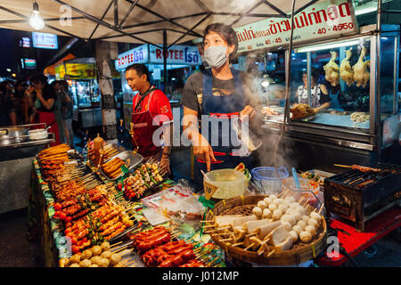 Chiang Mai, Thailand - August 27, 2016: Young men sell satay at the Saturday Night Market on August 27, 2016 in Chiang Mai, Thailand.