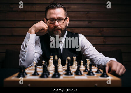 Pensive male chess player in glasses thinking about game strategy. Intelligence competition concept Stock Photo