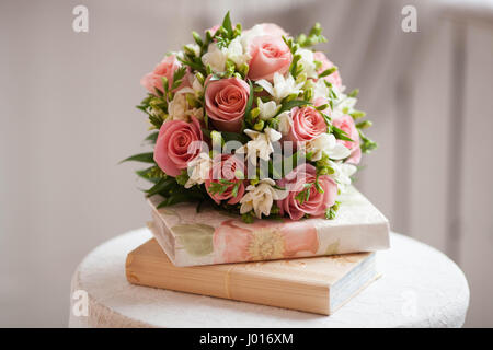 A beautiful delicate bouquet of roses and white irises on the books. Wedding decoration Stock Photo