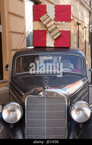 Santa Claus in an old car with a big red and gold present on top of the car. Picture was taken in Christmas time. Definitely a Santa Clause with style Stock Photo