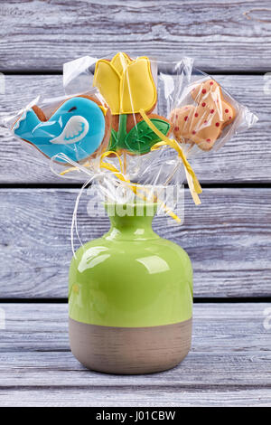 Vase with cookies, wood background. Colorful biscuits wrapped in plastic. Stock Photo