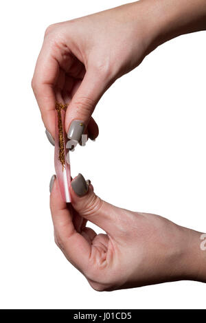 Hands of a woman rolling a cigarette with rolling tobacco on clear background. Soft focus. Stock Photo