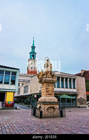 Poznan, Poland - May 6, 2014: Statue of St John Nepomuk holding cross on Old Market Square in the city center of Poznan, Poland. Spire of Old Town Hal