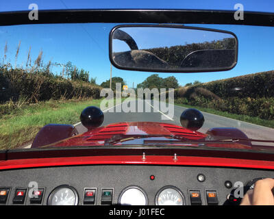 Looking through windscreen on a low red sports car with buttons on the dashboard Stock Photo