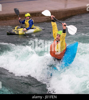 Young man holding his paddle over his head as he prepares to do a dive in his blue kayak. Stock Photo