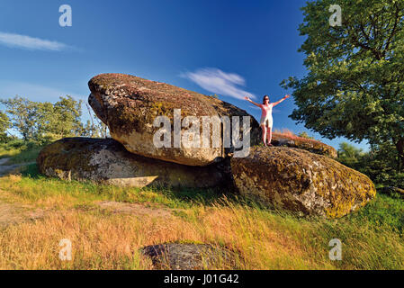 Woman standing on huge rock with outstretched arms Stock Photo