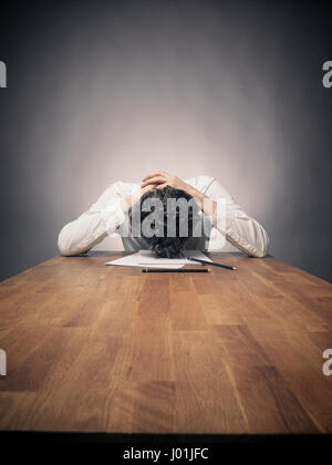 Crazy business man tired of working on a wooden office table, wide angle shot with space for text or image Stock Photo