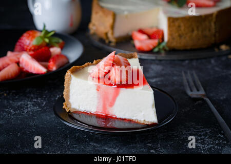 Cheesecake with fresh strawberries and strawberry syrup on black plate. Stock Photo