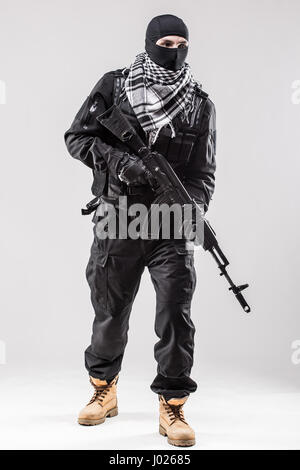 Terrorism concept: Terrorist holding a machine gun in his hands isolated over white Stock Photo