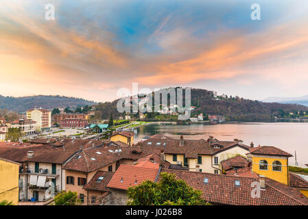 Lake Maggiore, Laveno, Italy. Picturesque sunrise. View towards the pier of the ferry, the railway station and part of the lake promenade Stock Photo