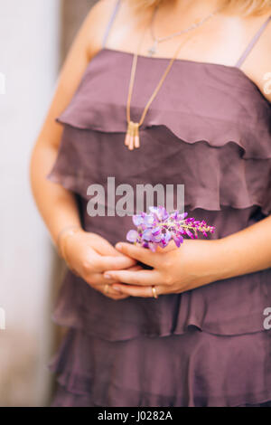 wisteria branch in the hands of a girl in a purple dress Stock Photo