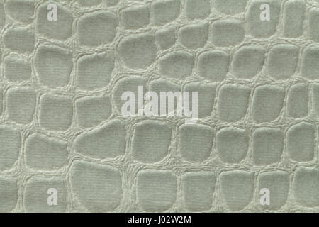 Light green background from a soft upholstery textile material, closeup. Fabric with pattern imitating crocodile skin.. Textured backdrop. Stock Photo