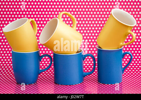 Colorful coffee mugs on pink background with white dots Stock Photo