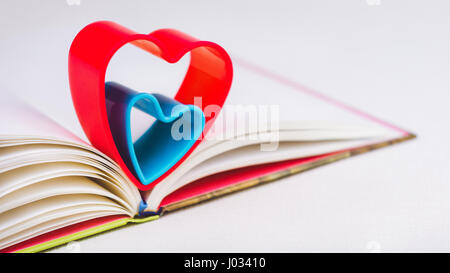 Red and blue hearts over diary book on white table Stock Photo