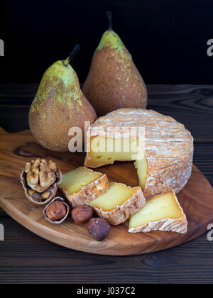 Soft washed-rind cheese, walnut, hazelnuts and pears on the wooden board Stock Photo