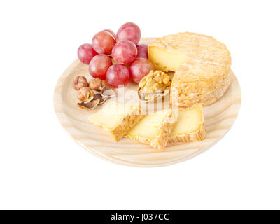 Soft washed-rind cheese, hazelnuts, walnut and red grape on the textured wooden board isolated on white Stock Photo