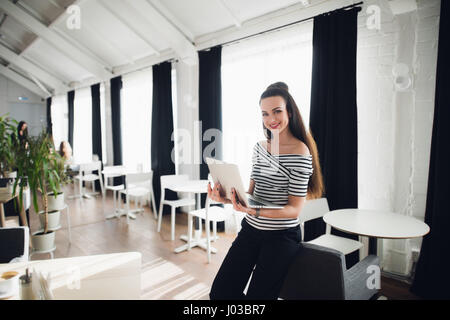 Smiling Attractive Woman Working on Laptop in Cafe. Stock Photo