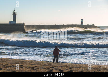 Man fishing from the beach in Foz do Douro district of Porto city, second largest city in Portugal. View with Felgueiras Lighthouse Stock Photo