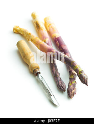 Fresh purple asparagus with peeler isolated on white backgrund. Stock Photo