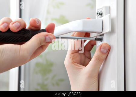 Screwing the screw of window handle on pvc window. Stock Photo