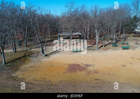 Old benches, some broken, and empty swingset in neglected park Stock Photo