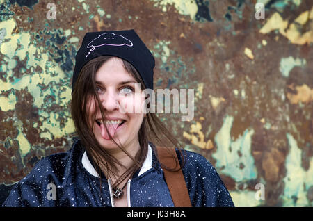 Young girl showing tongue, having fun on colorful grunge background Stock Photo