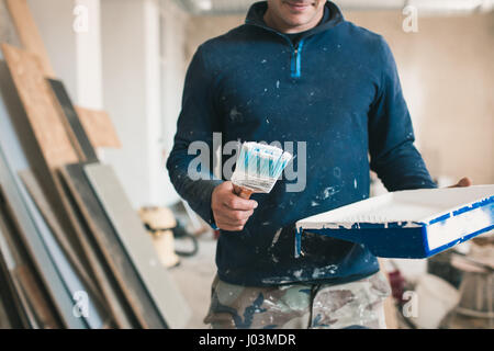 The painter in working clothes paints an imaginary wall. Focus on the brush Stock Photo