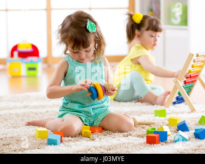 Children toddler and preschooler girls play logical toy learning shapes, arithmetic and colors at home or nursery Stock Photo