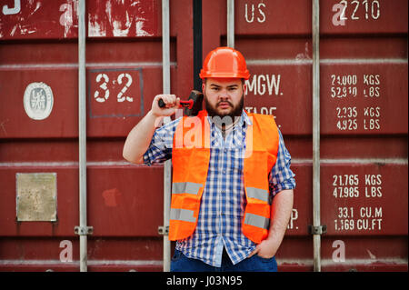 Brutal beard worker man suit construction worker in safety orange helmet with hammer on hand. Stock Photo
