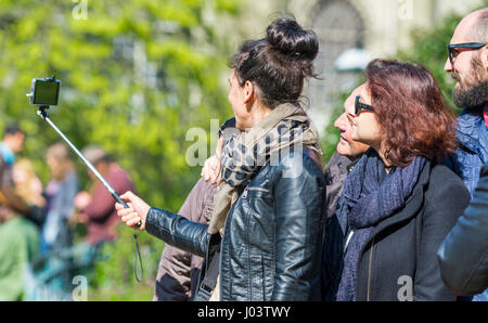 Tourists taking selfis photographs using a smartphone attached to a selfie stick. Stock Photo