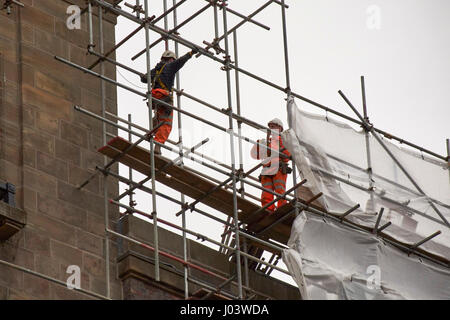 workmen with safety gear and harnesses on a high scaffold building Liverpool UK Stock Photo