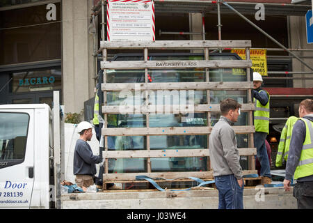 workmen delivering glass panels to commercial development city centre Liverpool UK Stock Photo