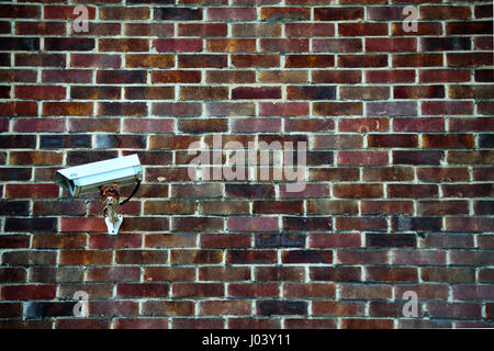 CCTV surveillance camera mounted against a brick wall, UK Stock Photo
