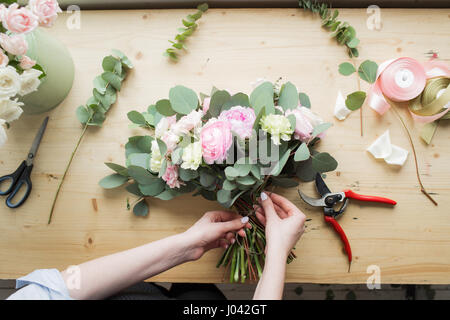 Florist at work: pretty young woman making fashion modern bouquet of different flowers Stock Photo