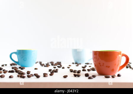Colorful coffee cups on white table with beans Stock Photo
