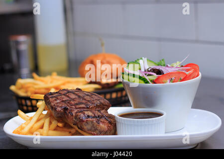 Chargrilled Grass Fed Rump Steak with chips salad and pepper sauce burger on side Stock Photo