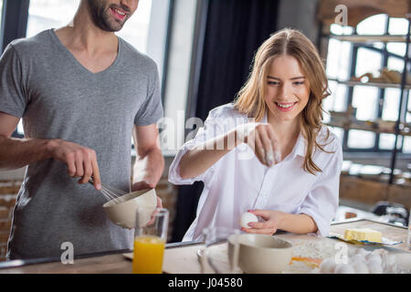 Young couple cooking together with eggs and flour in kitchen Stock Photo
