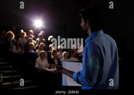 Male teacher giving a speech in a lecture hall to students and teachers. Stock Photo