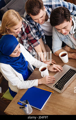 Positive smiling international students sitting in the cafe Stock Photo