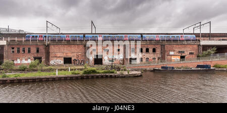 Manchester, England, UK - June 16, 2012: A First TransPennine Express Class 185 diesel passenger train runs across a scruffy brick viaduct beside the  Stock Photo