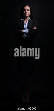 Happy business woman wearing black suit standing and folding arms Stock Photo